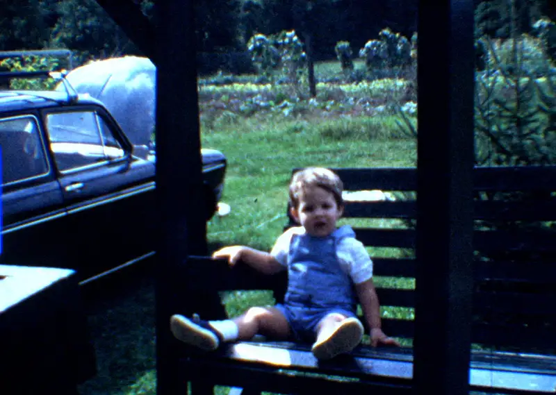 Toddler sitting on a bench with the 1968 VW Squareback in the background