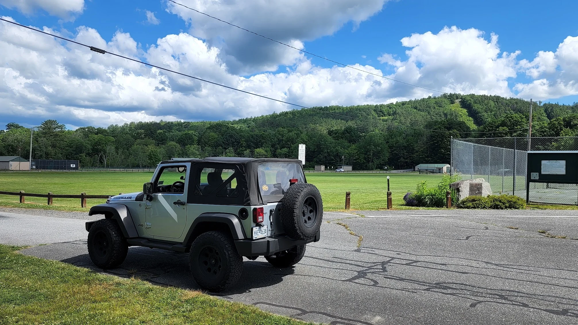 2012 Jeep Wrangler JK in green, parked with New Hampshire hills in the background