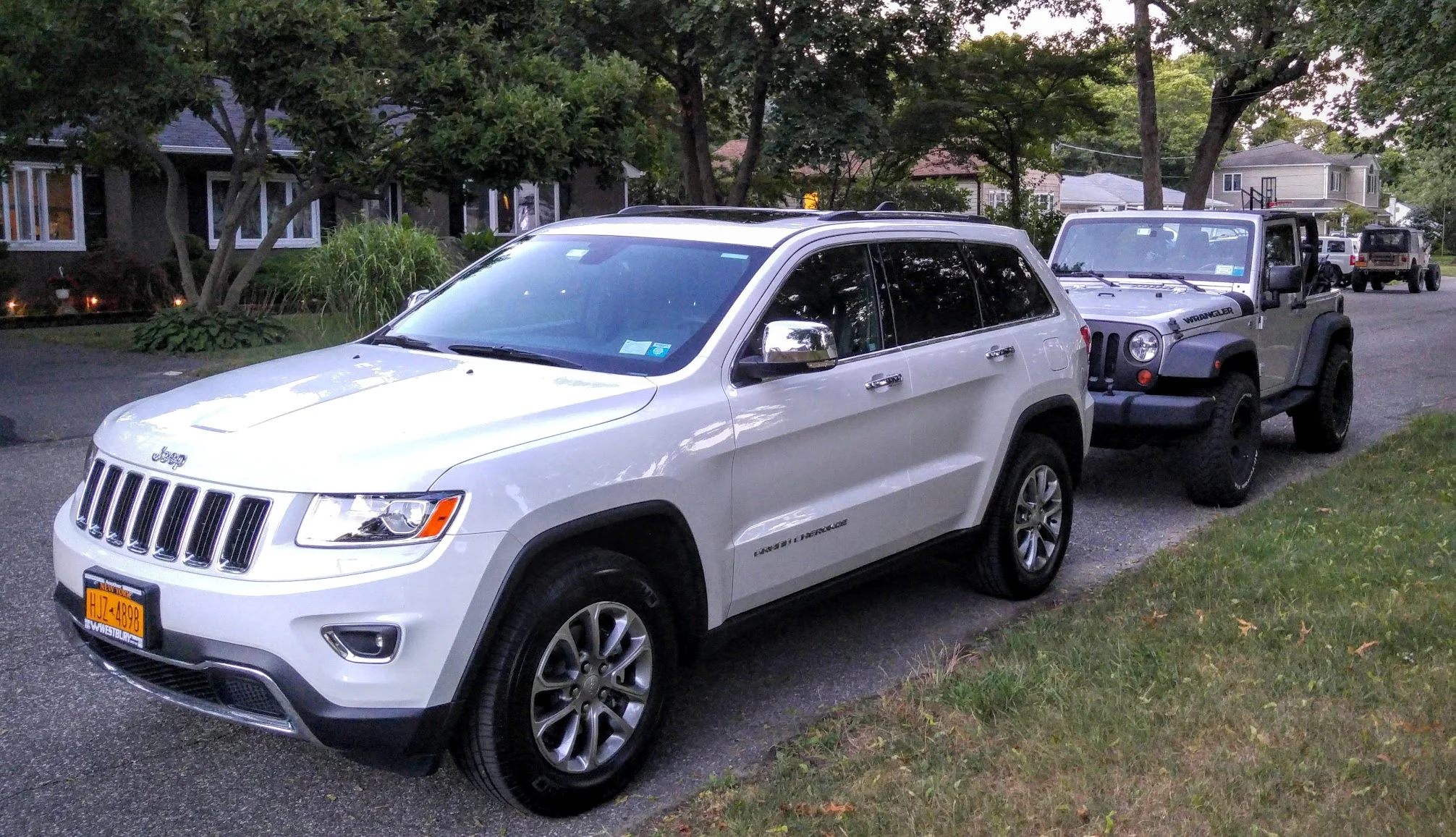 2016 Jeep Grand Cherokee in white with JK Wrangler behind it