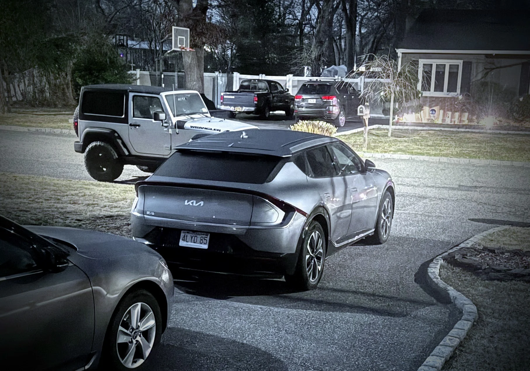 Hertz Kia EV6 Wind RWD rental parked in driveway, Wrangler in background
