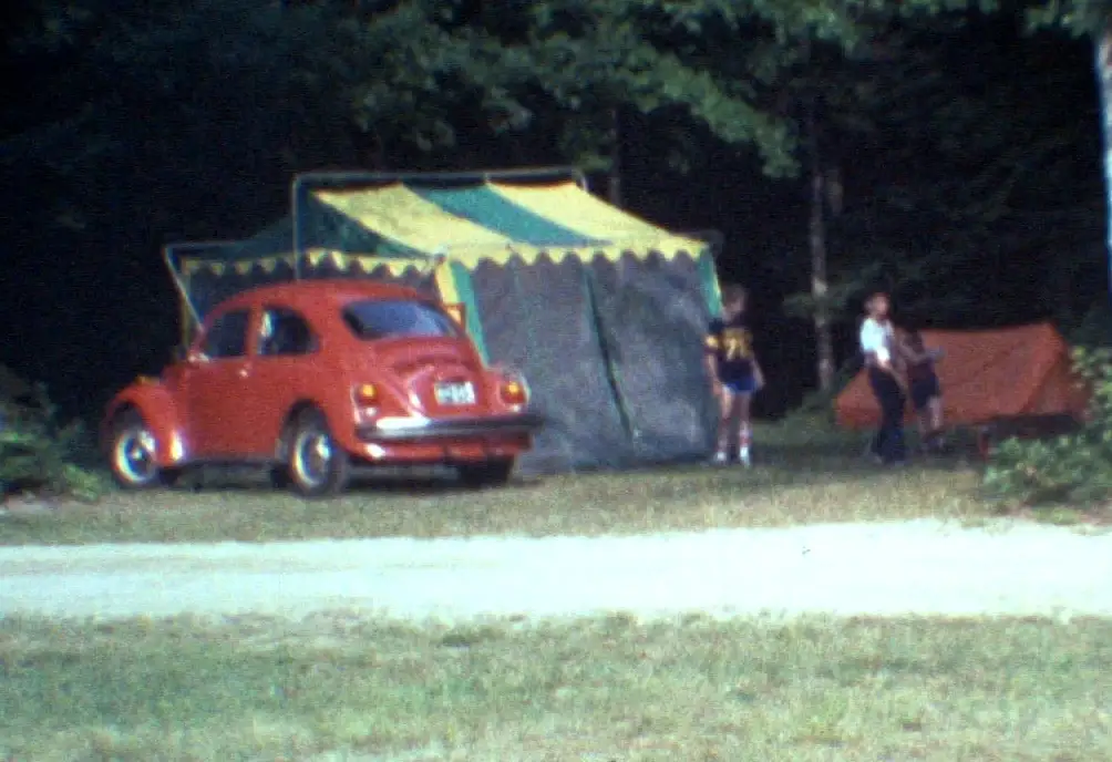 Red 1973 VW Super Beetle at a campsite with a green and yellow screen tent